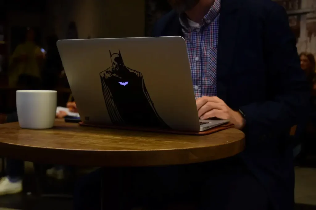 Person Using a Laptop That Has a Batman Sticker