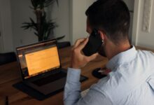 Man taking a phone call while working at a laptop