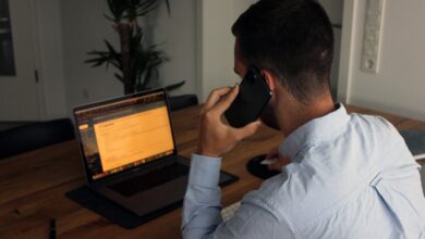 Man taking a phone call while working at a laptop