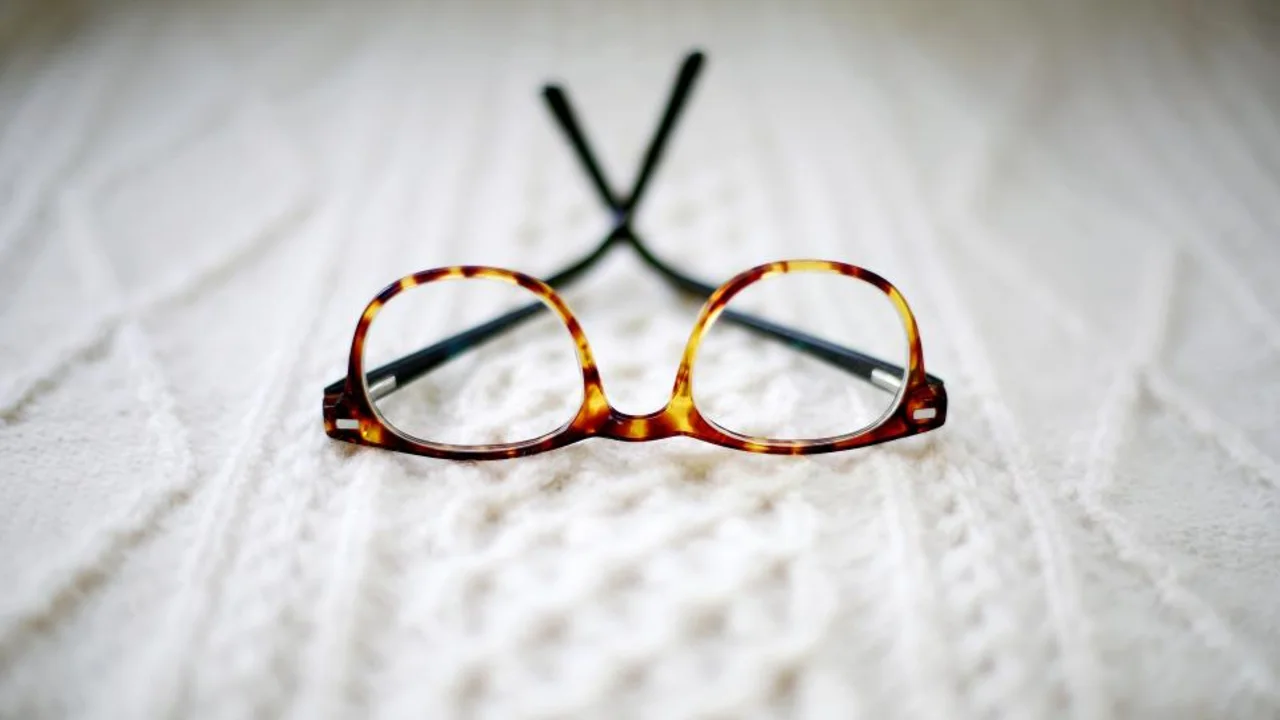 Tortoiseshell-frame glasses lying on a knitted blanket, illustrating everyday eyewear