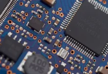 Macro close-up of a blue computer circuit board with surface-mount chips, representing the hardware behind AI web browsers