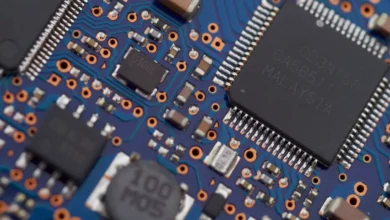 Macro close-up of a blue computer circuit board with surface-mount chips, representing the hardware behind AI web browsers
