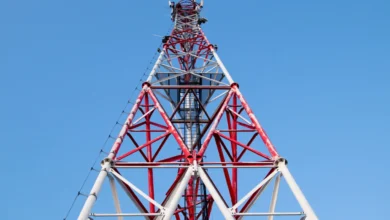 A red and white mobile network tower against a clear blue sky