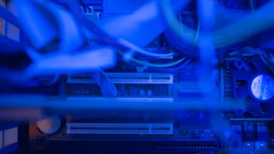 Close-up inside a gaming PC case showing cables, PCIe slots and a CPU cooler fan under blue light
