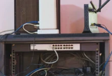 A home network rack with a router, switch and patch cables mounted on a wall