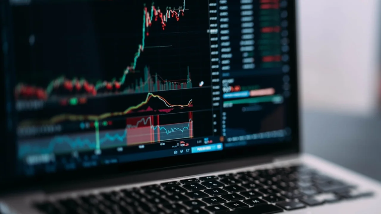 A smartphone displaying a social media chat beside a laptop showing a fake trading chart, illustrating investment scams on social media