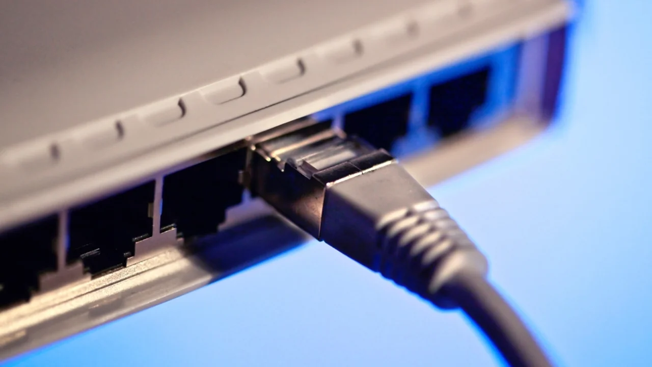 Close-up of a network router with an ethernet cable plugged into its port, blue lighting
